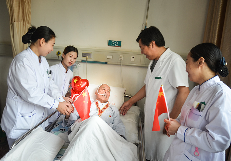 4峰峰总医院国庆节当日内三科病房里医护们为93岁的患者秦武平带上中共中央、国务院中央军委宣告的国庆70周年留想章并和他一路欢度国庆，秦爷爷曾参与过南征惫亟、孟良崮战争、淮海战争、抗美援朝是一名老武士、老革命 作者：肖建华(2).jpg